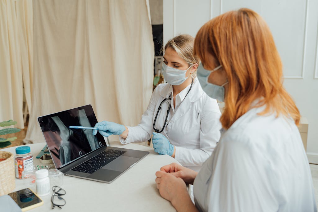 Doctor explains X-ray results to patient using a laptop in a clinic setting.